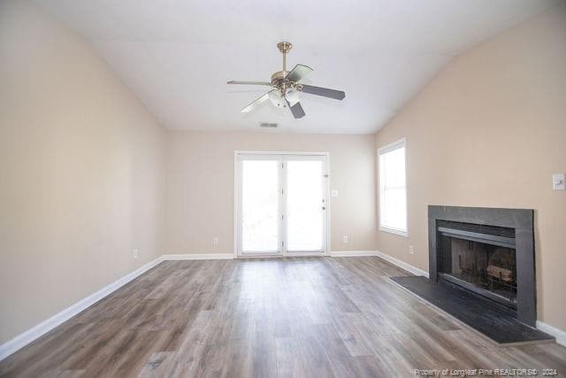 unfurnished living room featuring dark hardwood / wood-style floors, vaulted ceiling, ceiling fan, and a healthy amount of sunlight