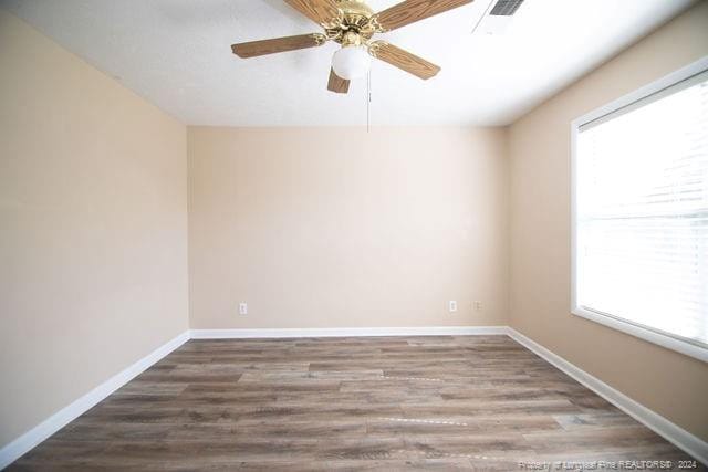 empty room with ceiling fan, hardwood / wood-style floors, and a healthy amount of sunlight