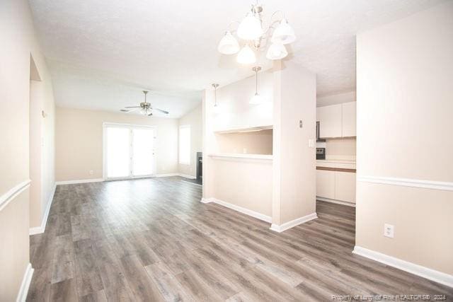 unfurnished room with hardwood / wood-style flooring, ceiling fan with notable chandelier, and vaulted ceiling