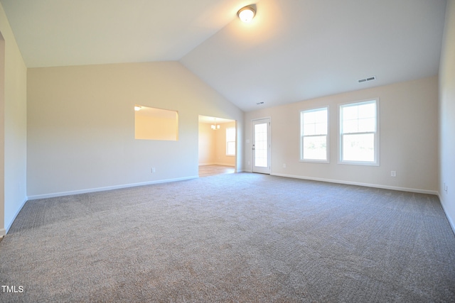 carpeted empty room featuring lofted ceiling and a chandelier