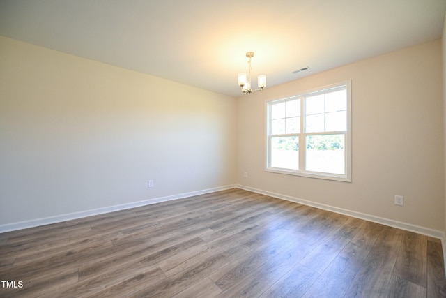 unfurnished room featuring dark wood-type flooring and a chandelier