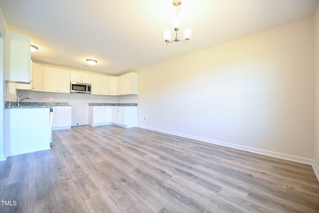 kitchen featuring white cabinetry, decorative light fixtures, a chandelier, and light wood-type flooring