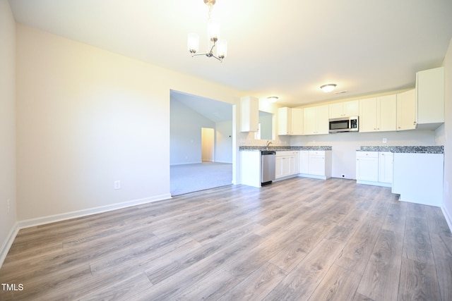 kitchen with pendant lighting, appliances with stainless steel finishes, a notable chandelier, light hardwood / wood-style floors, and white cabinets