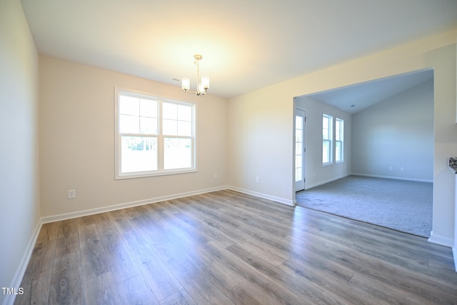 empty room featuring wood-type flooring, a chandelier, and vaulted ceiling