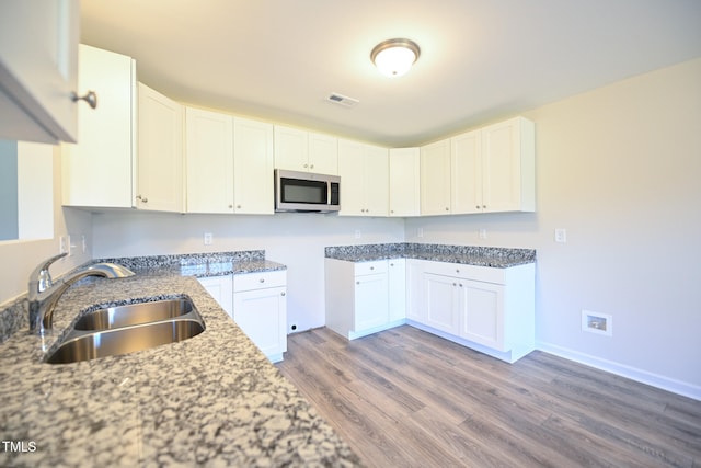 kitchen with white cabinetry, wood-type flooring, sink, and dark stone counters