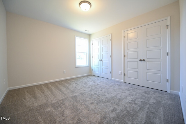 unfurnished bedroom featuring multiple closets and carpet flooring