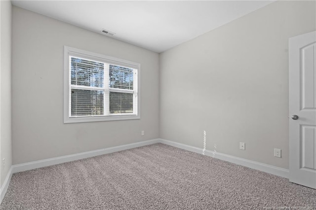 spare room featuring carpet, visible vents, and baseboards