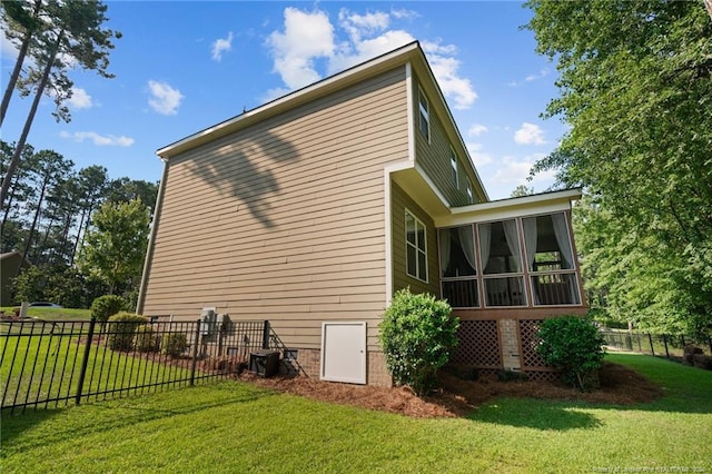 view of side of home featuring a sunroom, a yard, and fence