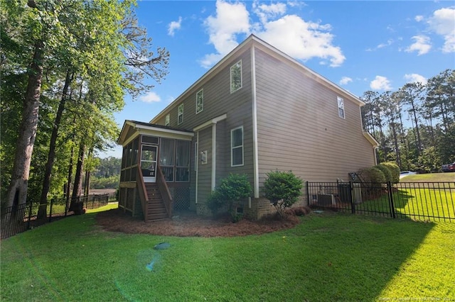 rear view of property featuring a yard, a fenced backyard, a sunroom, and stairs