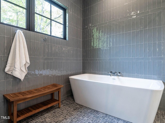 bathroom with tile patterned floors, a bathtub, and tile walls