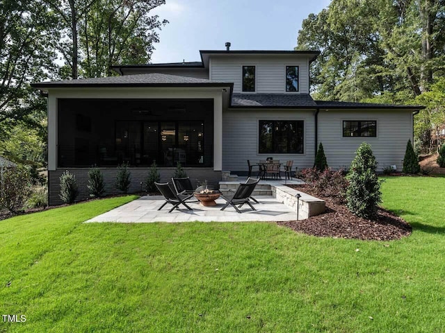 back of house featuring a lawn, a patio area, a sunroom, and a fire pit