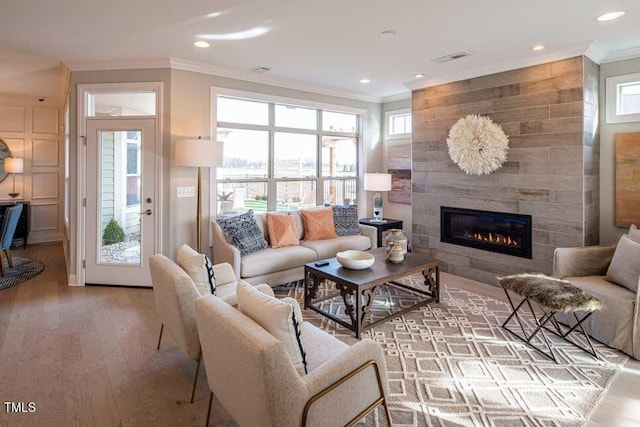 living room with crown molding, a fireplace, and hardwood / wood-style flooring