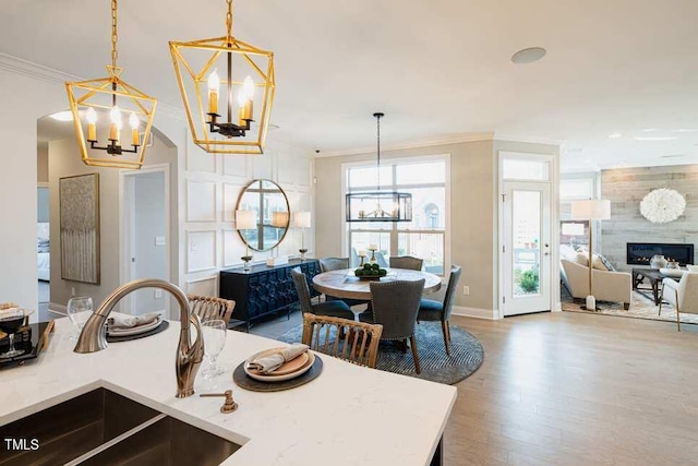 dining room with ornamental molding, sink, a large fireplace, and a chandelier