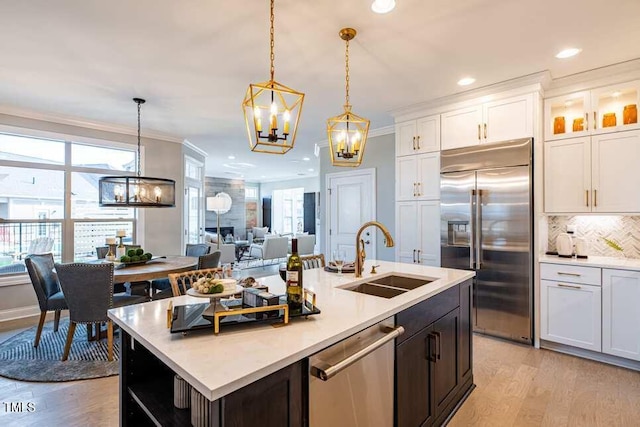 kitchen with sink, appliances with stainless steel finishes, white cabinetry, hanging light fixtures, and plenty of natural light