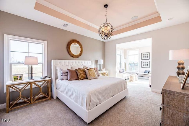 carpeted bedroom featuring multiple windows, ornamental molding, an inviting chandelier, and a tray ceiling