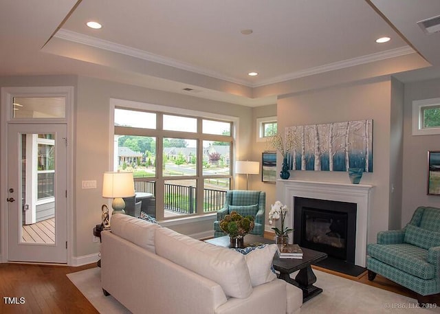 1005 Bridgeforth Ln, Durham, NC 27713 - living room featuring a raised ceiling, hardwood / wood-style flooring, a glass covered fireplace, plenty of natural light, and ornamental molding