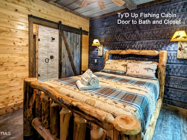 bedroom with a barn door, wooden ceiling, hardwood / wood-style flooring, and wood walls