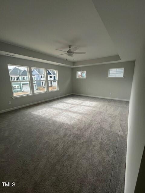 carpeted empty room featuring ceiling fan and a tray ceiling