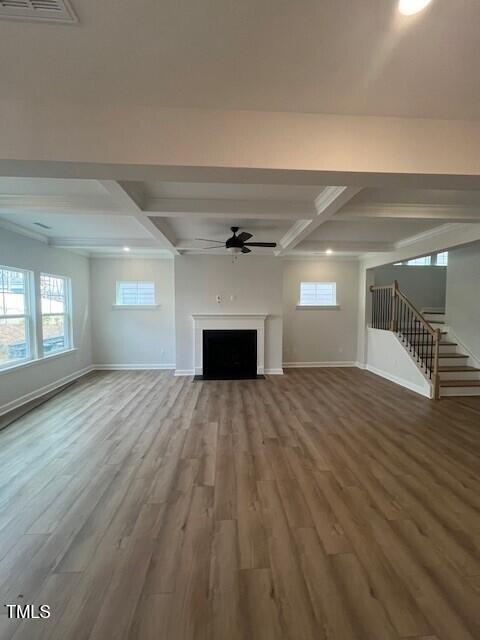 unfurnished living room with beamed ceiling, wood-type flooring, ceiling fan, and coffered ceiling