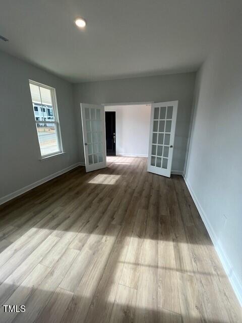 spare room featuring french doors and hardwood / wood-style flooring