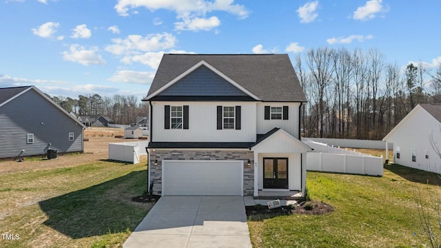 view of front of house featuring an attached garage, fence, driveway, stone siding, and a front yard