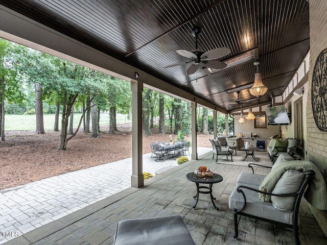 view of patio with outdoor dining space, a ceiling fan, and an outdoor living space with a fire pit