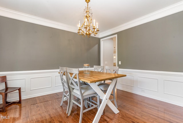 dining space with crown molding, wood-type flooring, and a notable chandelier