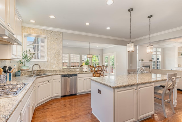 kitchen featuring a center island, light hardwood / wood-style floors, ornamental molding, stainless steel appliances, and pendant lighting