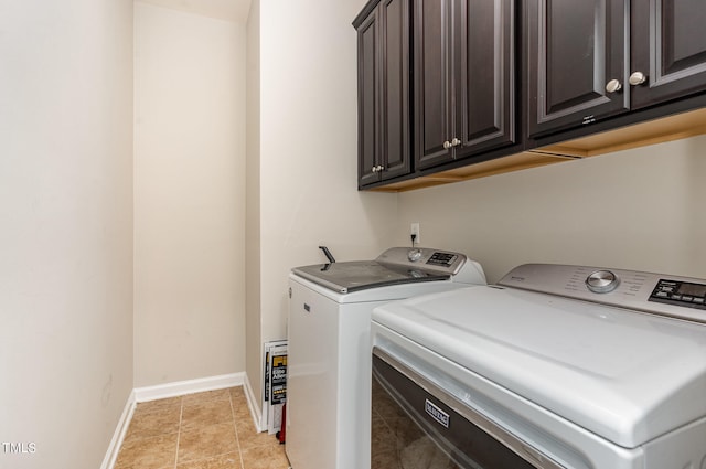 clothes washing area with cabinets, washing machine and dryer, and light tile floors