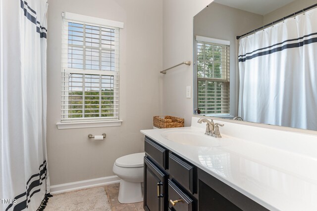 bathroom with tile floors, a wealth of natural light, toilet, and vanity