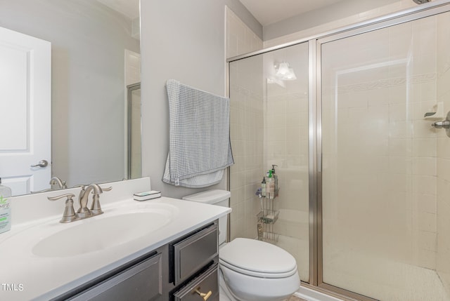 bathroom with a shower with shower door, toilet, and vanity