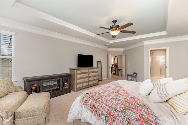 carpeted bedroom with a tray ceiling, crown molding, and ensuite bath