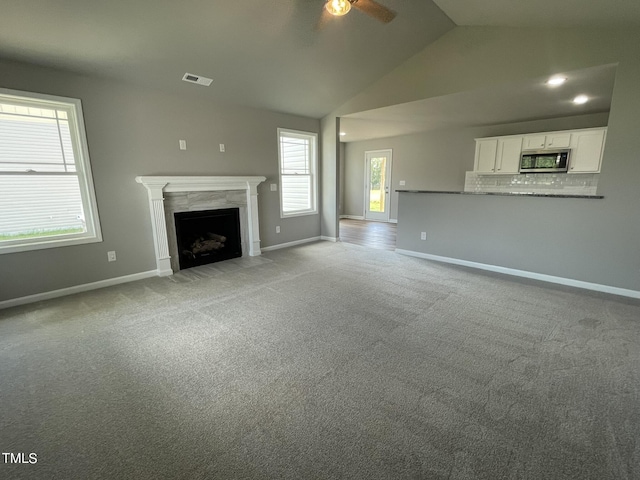 unfurnished living room featuring light carpet, visible vents, a ceiling fan, and a premium fireplace