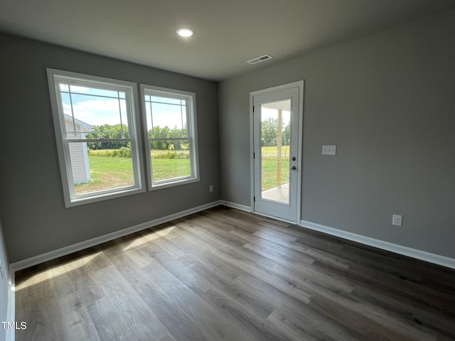 empty room with baseboards, dark wood-style floors, visible vents, and plenty of natural light
