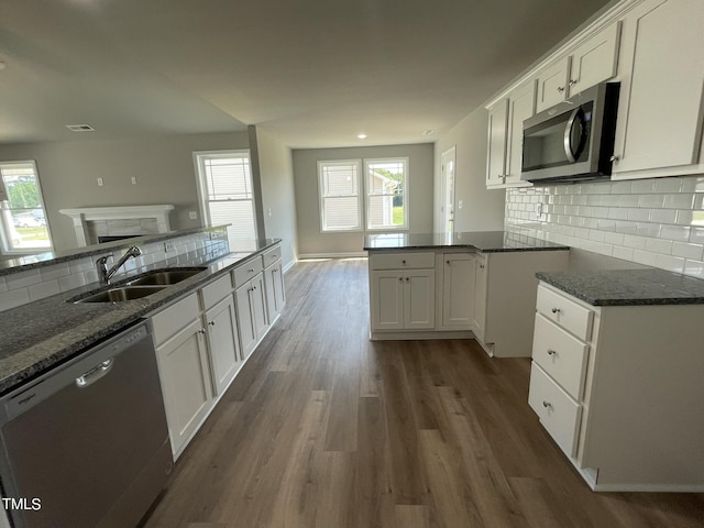 kitchen with dark stone counters, white cabinets, a sink, and stainless steel appliances