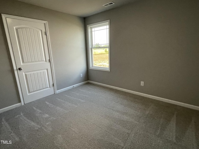 spare room with baseboards, carpet floors, and visible vents