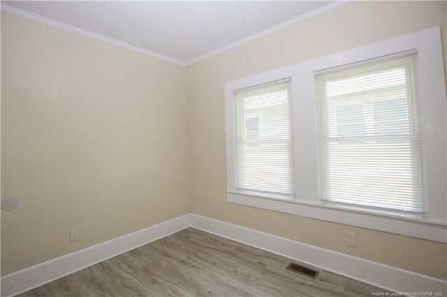 unfurnished room featuring visible vents, baseboards, crown molding, and wood finished floors