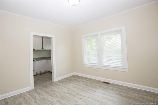 interior space featuring baseboards, light wood-type flooring, crown molding, and visible vents