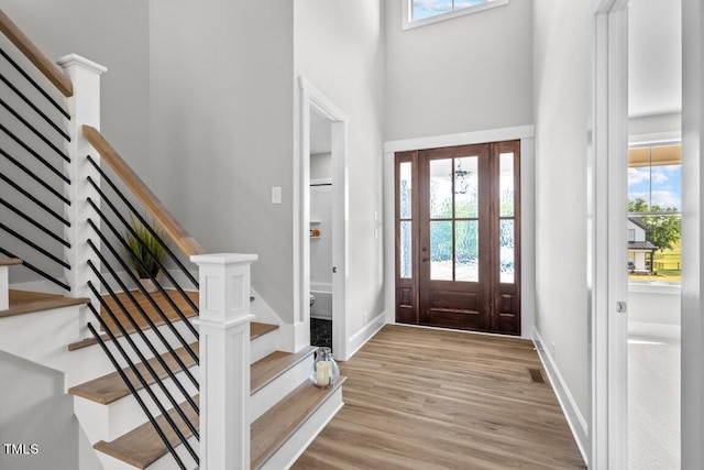 foyer entrance featuring a healthy amount of sunlight, light wood-type flooring, and a high ceiling