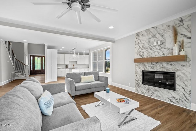 living room featuring a premium fireplace, dark hardwood / wood-style floors, ceiling fan, and ornamental molding