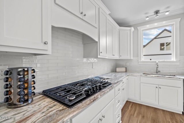 kitchen with white cabinetry, black gas stovetop, sink, and light stone counters