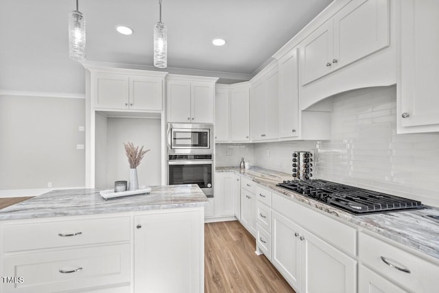 kitchen with appliances with stainless steel finishes, pendant lighting, white cabinetry, light stone countertops, and light wood-type flooring