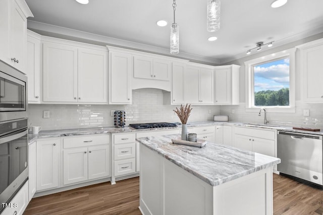 kitchen featuring a kitchen island, appliances with stainless steel finishes, white cabinetry, sink, and hanging light fixtures