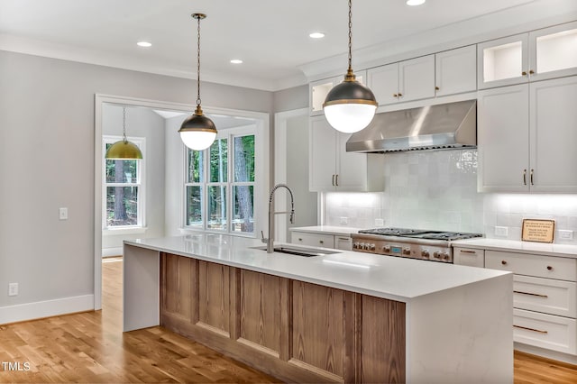 kitchen featuring sink, white cabinetry, an island with sink, and extractor fan