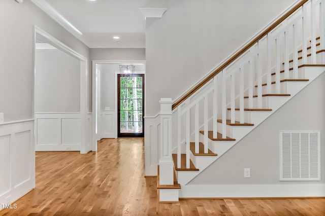 foyer entrance featuring light wood-type flooring, an inviting chandelier, and ornamental molding