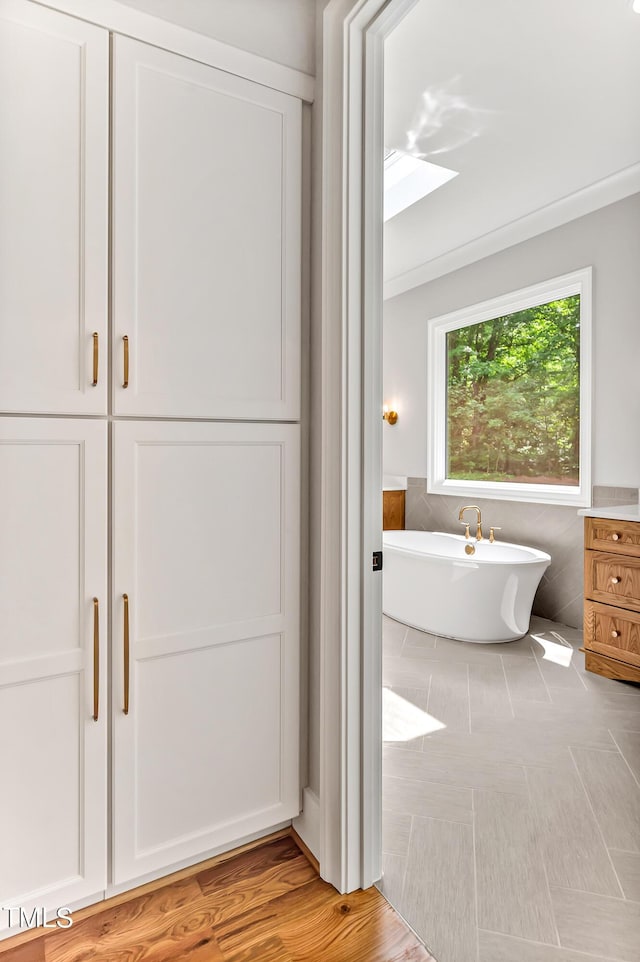 bathroom featuring a tub to relax in and crown molding