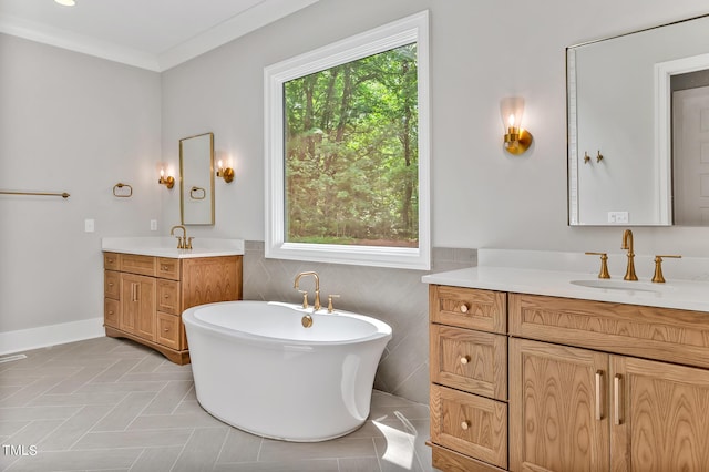 bathroom featuring a bathing tub, vanity, ornamental molding, and a wealth of natural light