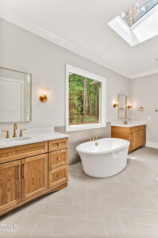 bathroom with vanity, a skylight, tile patterned floors, and crown molding