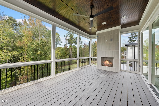 unfurnished sunroom with a fireplace, wooden ceiling, and ceiling fan