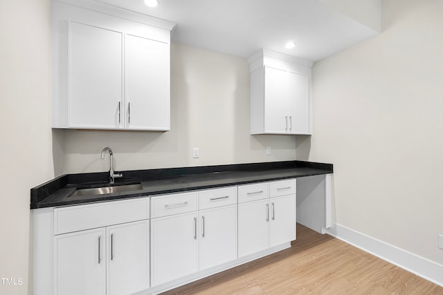 kitchen with white cabinetry, sink, and light hardwood / wood-style flooring